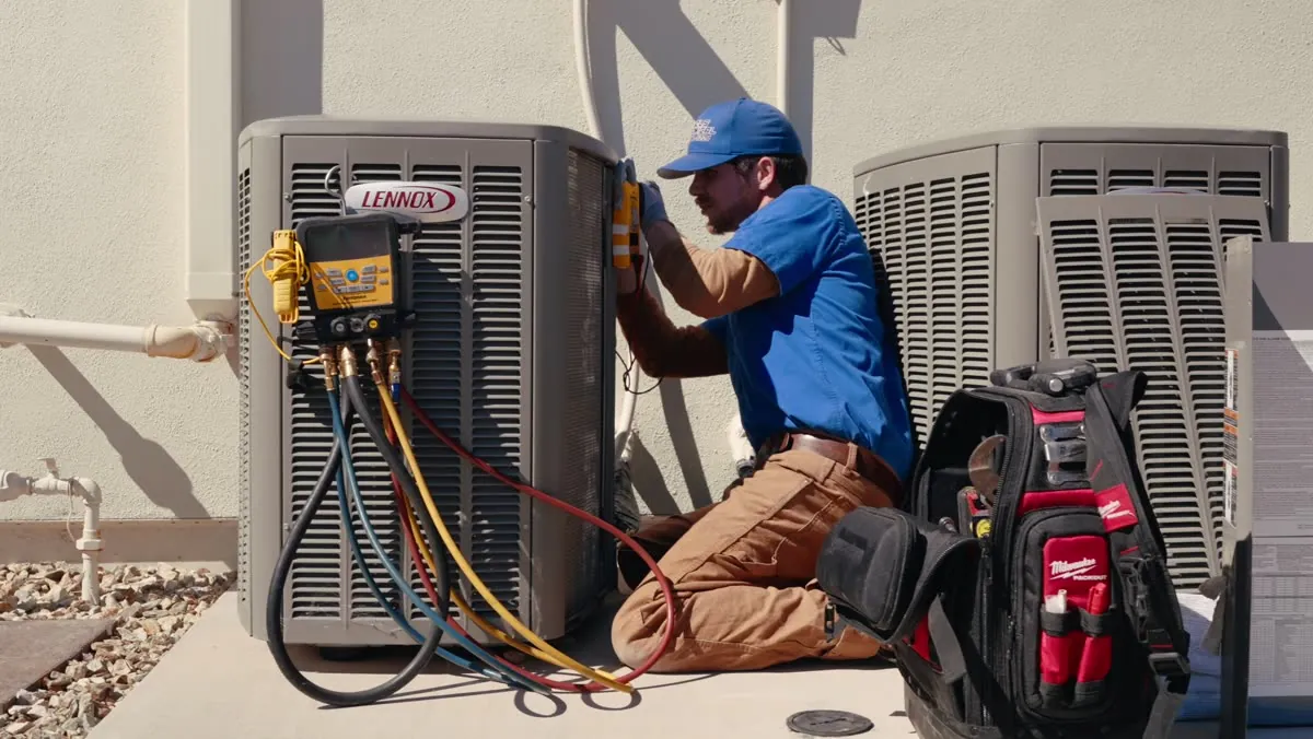 Nichols technician checking an AC condenser with refrigerant gauges